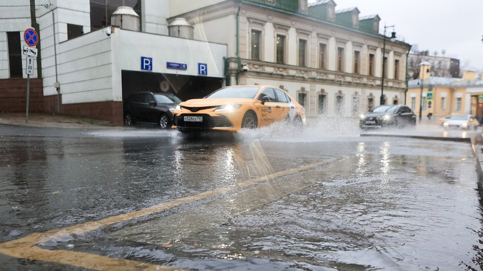 Такси проезжает по лужам в Москве