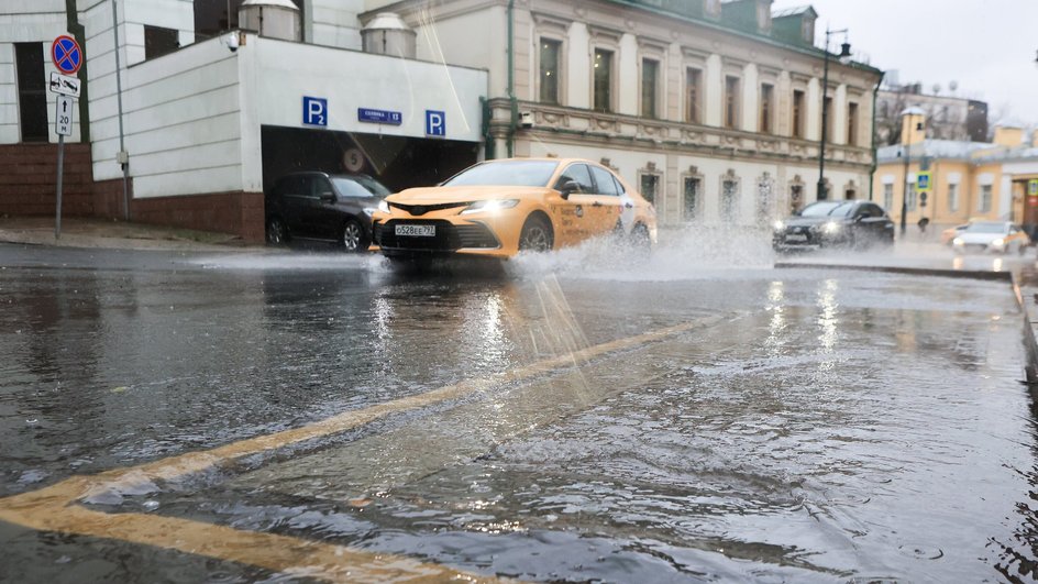 Такси проезжает по лужам в Москве