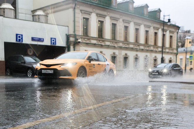 Такси проезжает по лужам в Москве