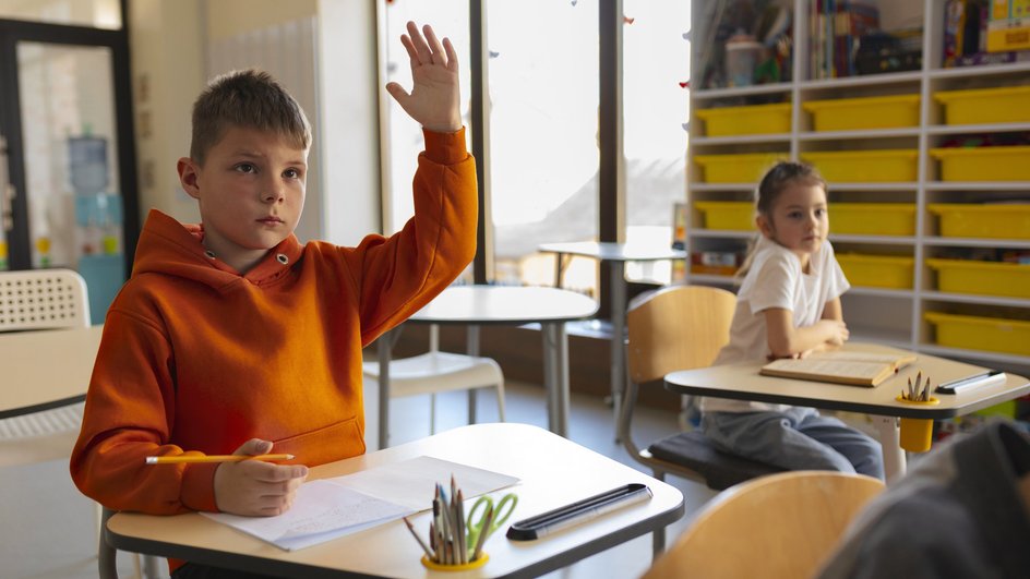 Мальчик поднимает руку на уроке для ответа