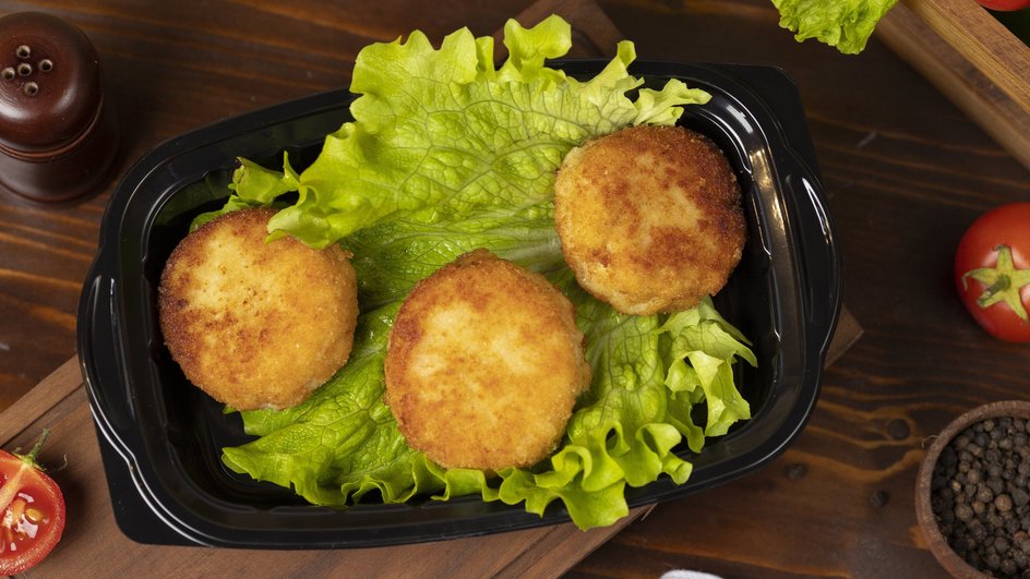 Вкусные биточки каши каши лежат на листе салата, который украшает прямоугольную черную тарелку Вкусные биточки каши каши лежат на листе салата, который украшает прямоугольную черную тарелку