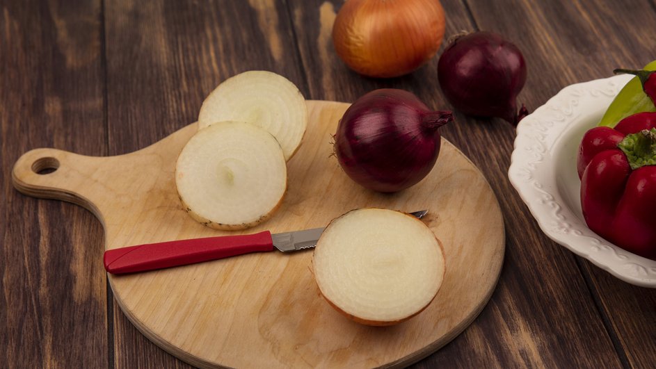 Деревянная кухонная доска с нарезанным луком лежит на столе Деревянная кухонная доска с нарезанным луком лежит на столе