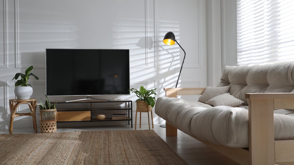 Телевизор в интерьере на фоне белой стены и дивана 