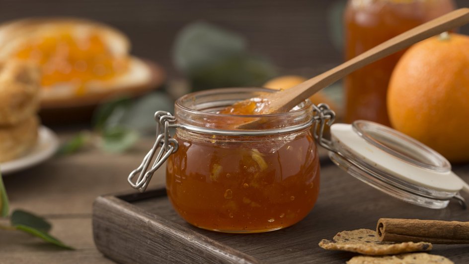 Банка варенья из кураги и апельсинов стоит на столе