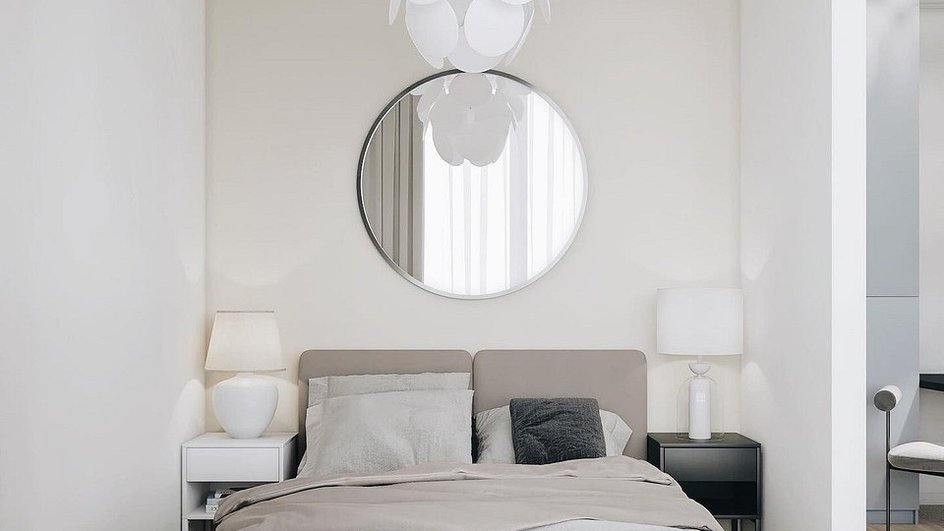 Светлая спальня с кроватью, круглым зеркалом и люстрой