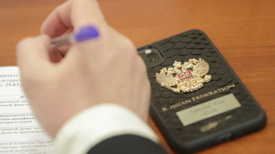 человек подписывает документ рядом со смартфоном человек подписывает документ рядом со смартфоном