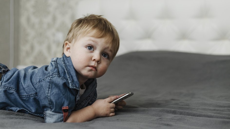 Малыш со смартфоном на кровати