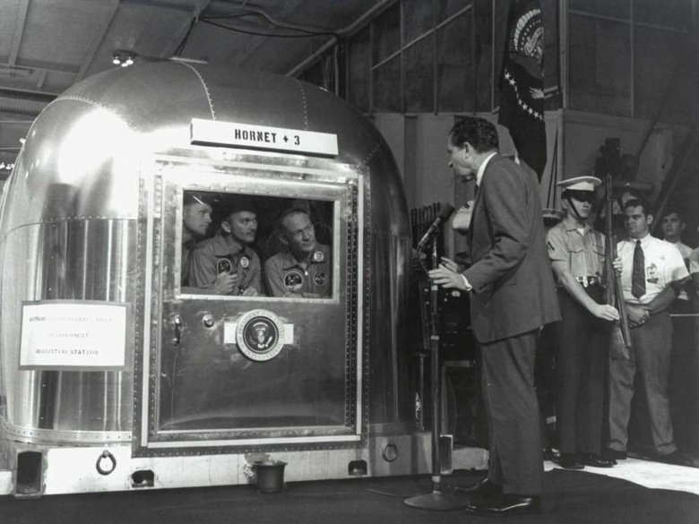 Космонавты «Аполлон-11» Нил Армстронг (слева), Майкл Коллинз и Эдвин Олдрин-младший сидят на карантинном участке на борту USS Hornet, президент Ричард Никсон поздравляет их с возвращением на Землю. Фото: Нью-Йорк Таймс
