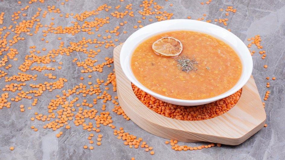 Тарелка супа-пюре из чечевицы с картофелем стоит на столе