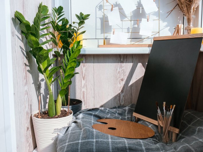 Мастерская на лоджии с черным креслом, столом и растением 
