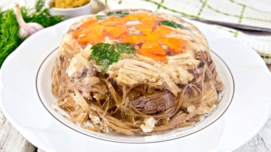 Холодец из курицы лежит на тарелке на столе Холодец из курицы лежит на тарелке на столе