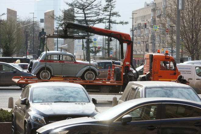 Эвакуатор перевозит автомобиль "Москвич-401" по улице в Москве