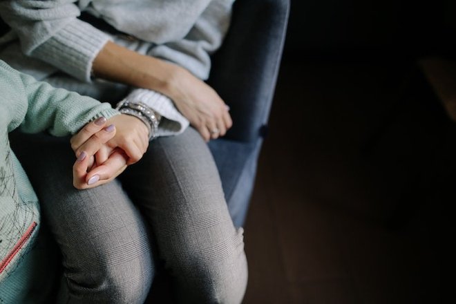 sitting-woman-in-gray-long-sleeved-shirt-holding-baby-s-hand-1684038.jpg