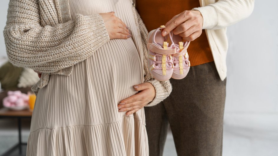 Муж протягивает беременной пинетки для новорожденного