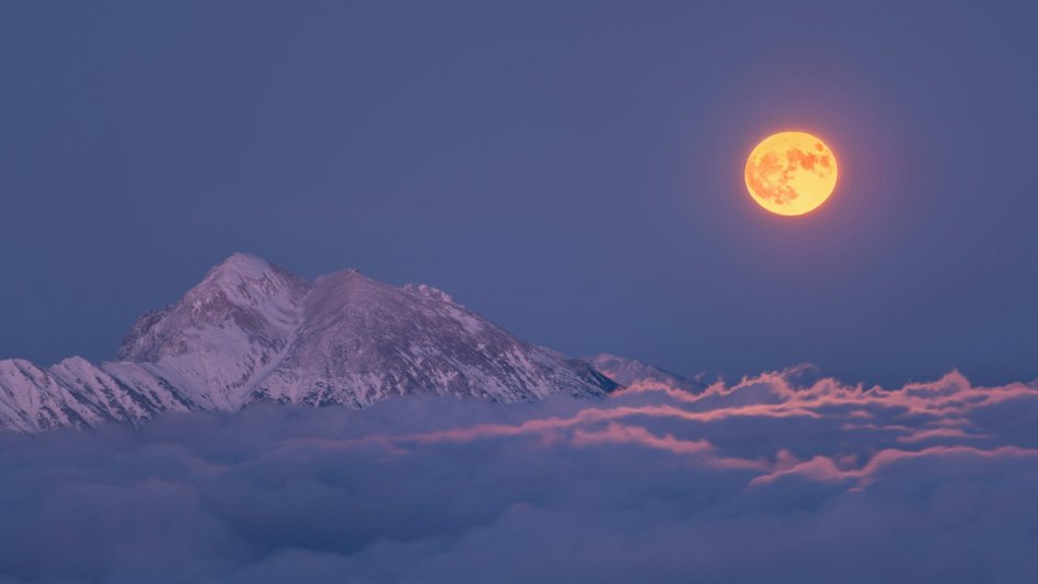 Оранжевая луна над облаками и горами