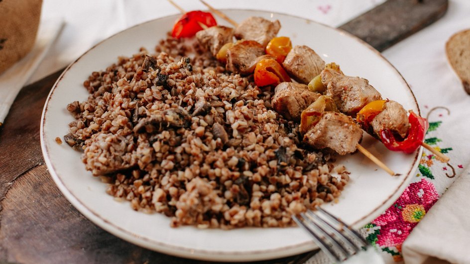 Тарелка гречки с мясом на шпажках стоит на доске Тарелка гречки с мясом на шпажках стоит на доске