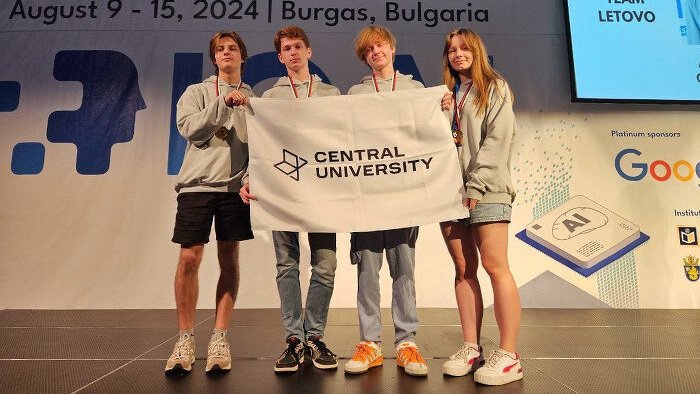 4 человека стоят на сцене и держат флаг с надписью "Central University" 4 человека стоят на сцене и держат флаг с надписью "Central University"