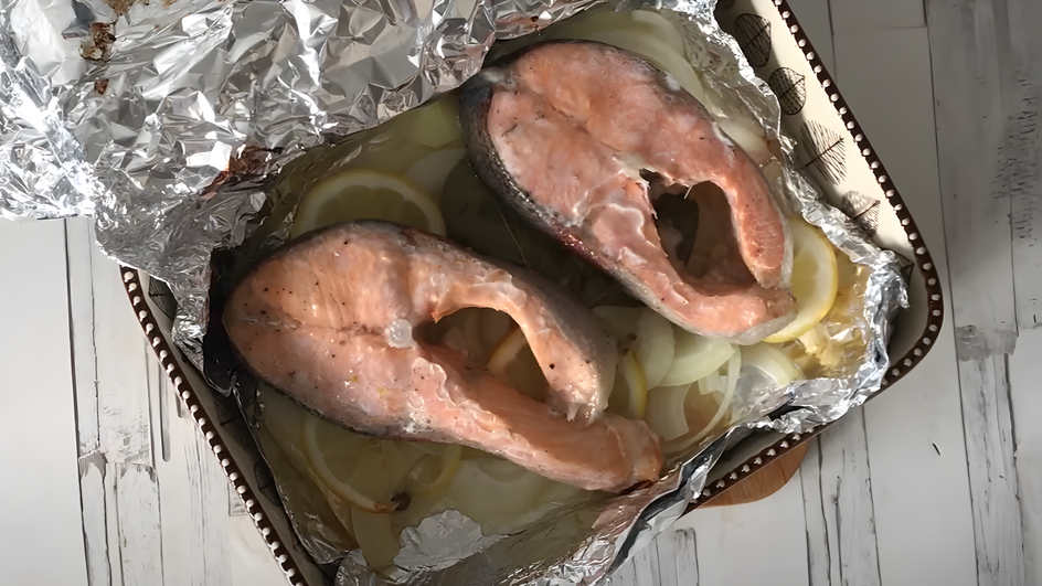Кусочки красной рыбы лежат на фольге Кусочки красной рыбы лежат на фольге