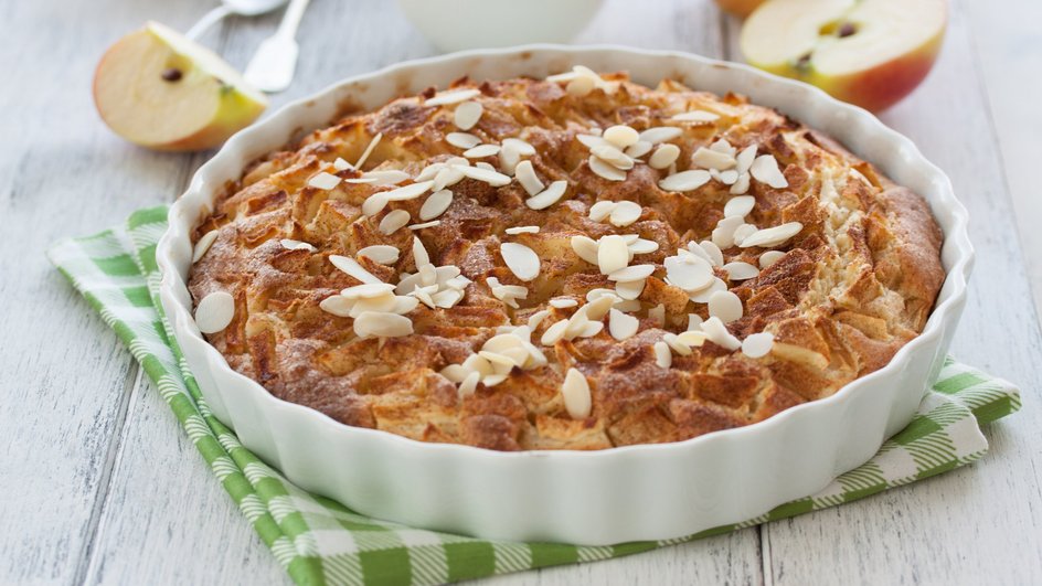 Шарлотка с черникой и лимоном лежит в форме на столе