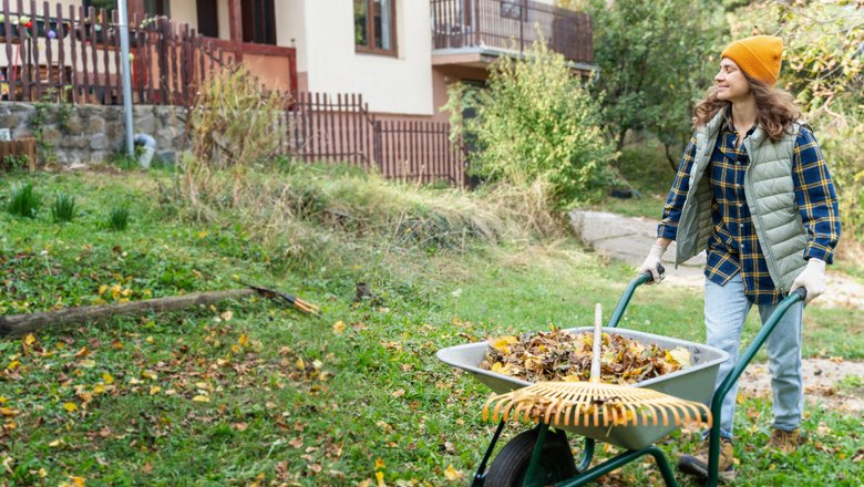 Мужчина осенью на улице перед дачей с тележкой проводит осенние работы