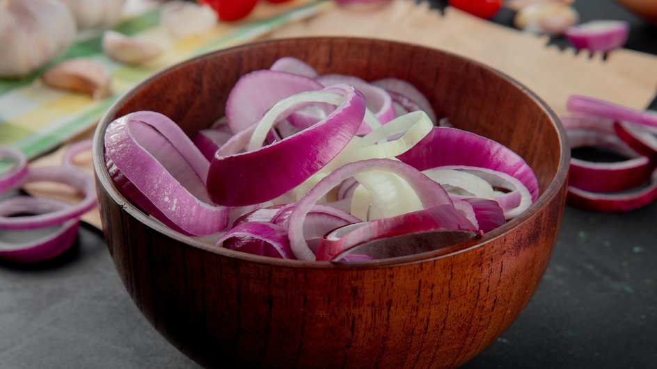 Деревянная миска, наполненная кольцами нарезанного лука Деревянная миска, наполненная кольцами нарезанного лука