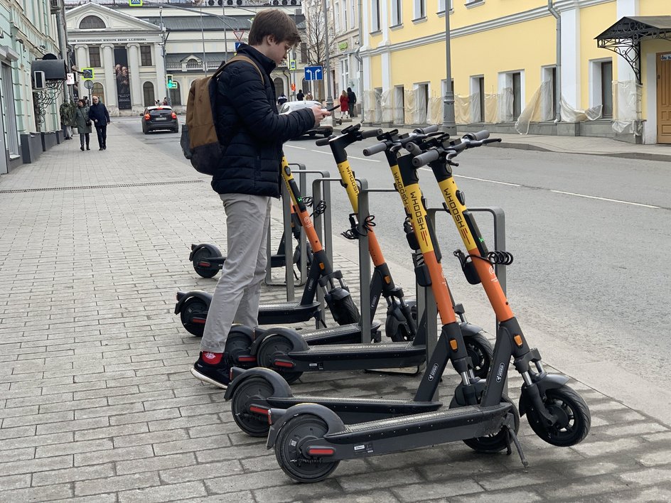 Молодой человек сканирует QR-код самоката Молодой человек сканирует QR-код самоката