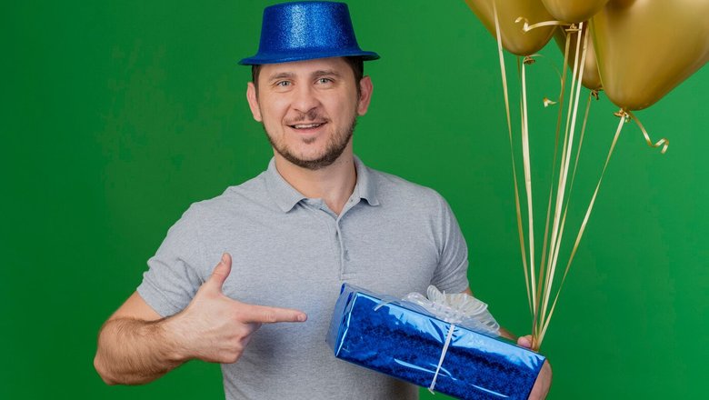 Мужчина в шляпе, с шариками и подарком на день рождения. Мужчина в шляпе, с шариками и подарком на день рождения.