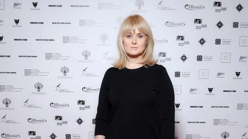 Киноактриса Анна Михалкова в черном платье стоит на красной ковровой дорожке