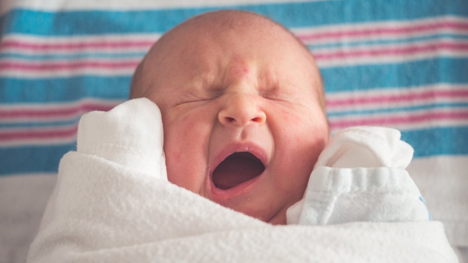зевающий новорожденный в пеленках