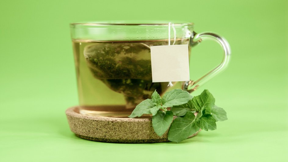 Зеленый чай в чашке на зеленом фоне