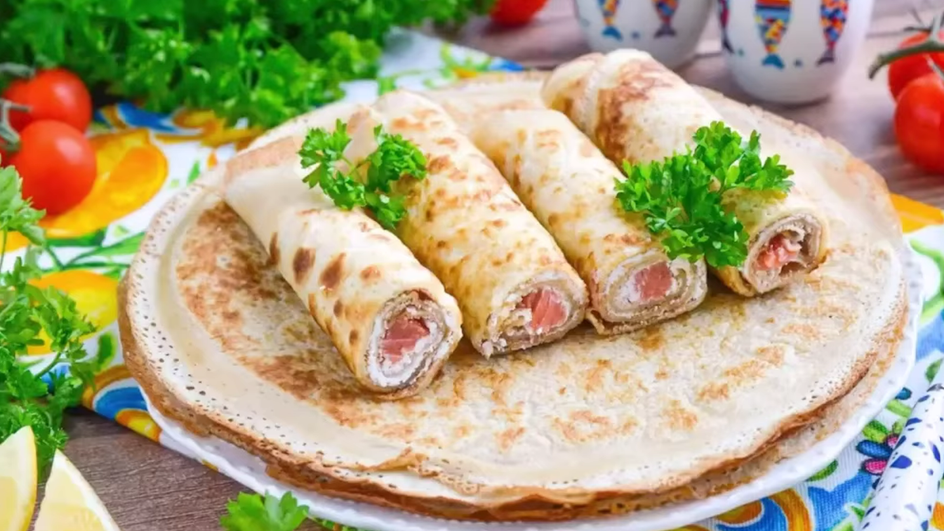 Блины с красной рыбой и сыром лежат на тарелке Блины с красной рыбой и сыром лежат на тарелке