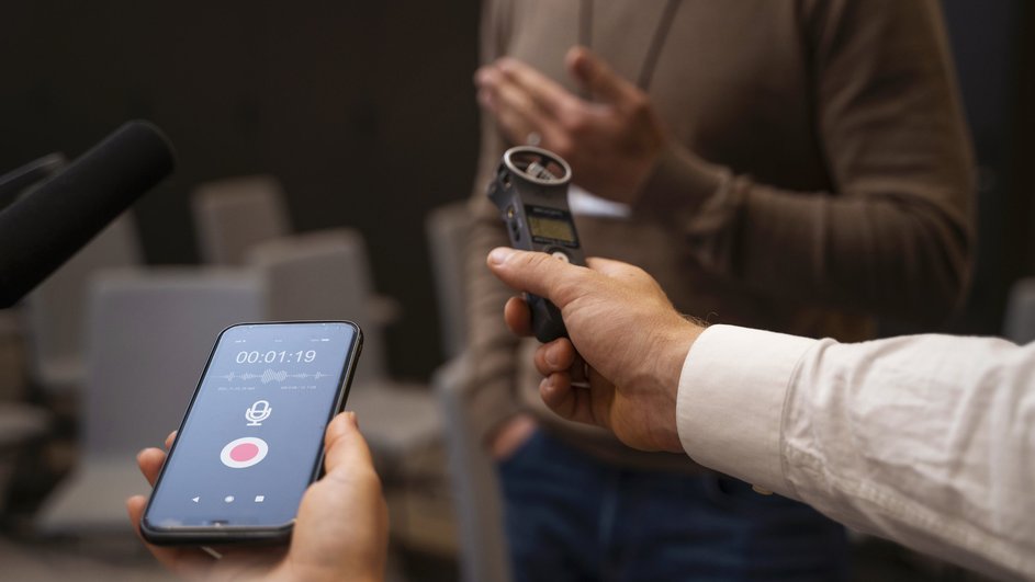 Журналисты с диктофоном в руках берут интервью Журналисты с диктофоном в руках берут интервью
