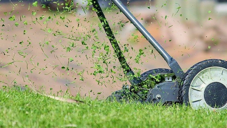 Газонокосилка подстригает траву для создания идеального газона