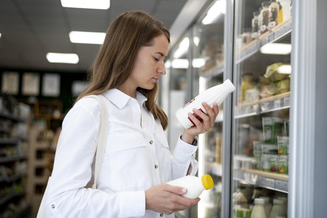 Девушка в магазине выбирает молоко, кефир