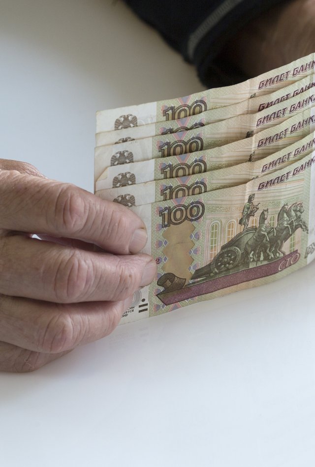 Пожилой человек держит в руках 500 рублей