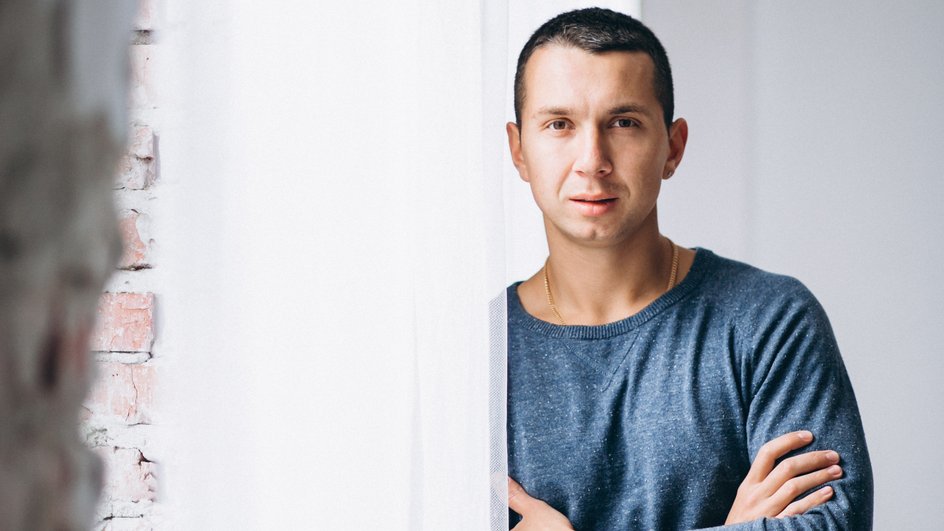 Жесткий мужчина-Овен с уверенным взглядом стоит возле окна Жесткий мужчина-Овен с уверенным взглядом стоит возле окна