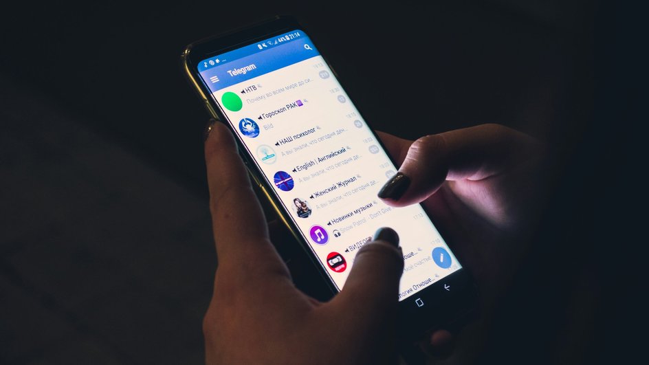 Женщина держит телефон с запущенным приложением Telegram Женщина держит телефон с запущенным приложением Telegram