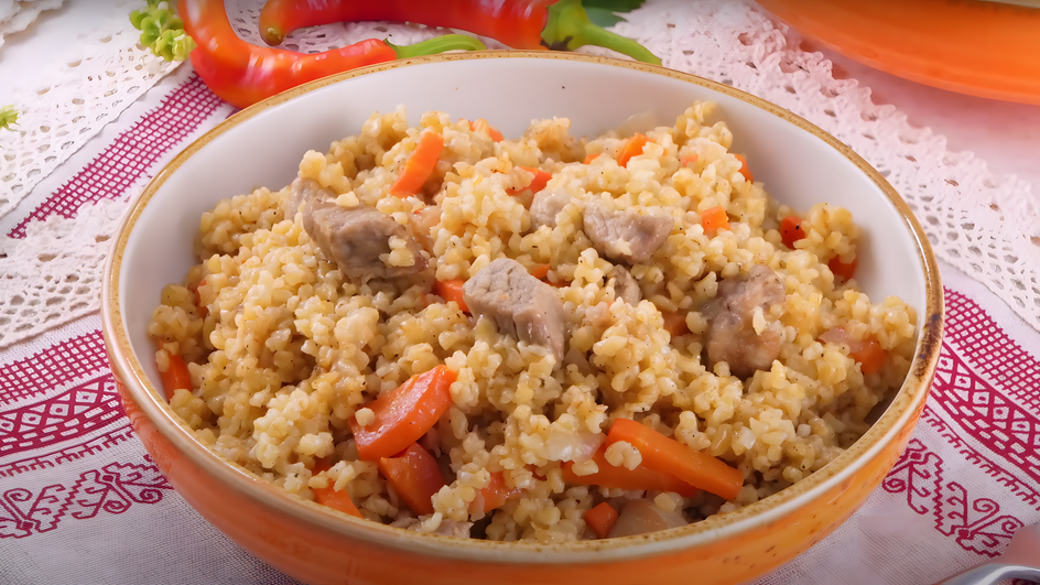 Тарелка пшеничной каши с мясом стоит на столе Тарелка пшеничной каши с мясом стоит на столе
