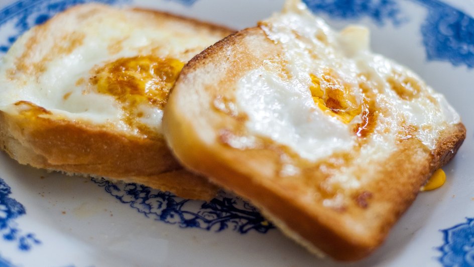 Гренки с сыром и яйцом лежат на тарелке Гренки с сыром и яйцом лежат на тарелке