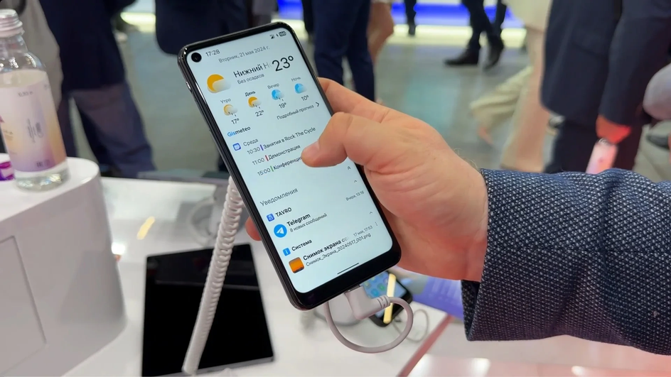 Участник выставки держит в руках смартфон на ОС Аврора