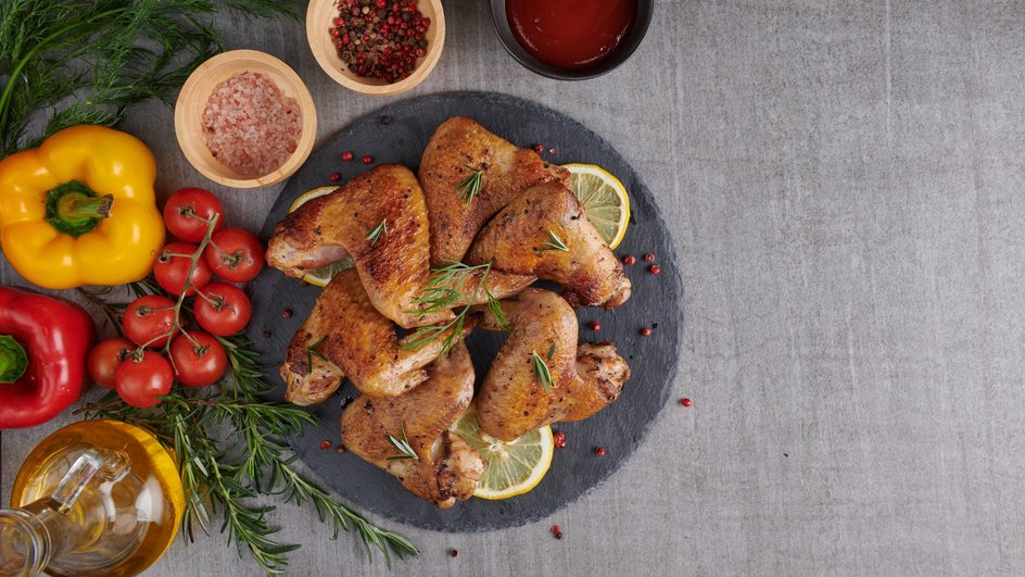 Шашлык из куриных крылышек лежит на подставке рядом с овощами и специями Шашлык из куриных крылышек лежит на подставке рядом с овощами и специями