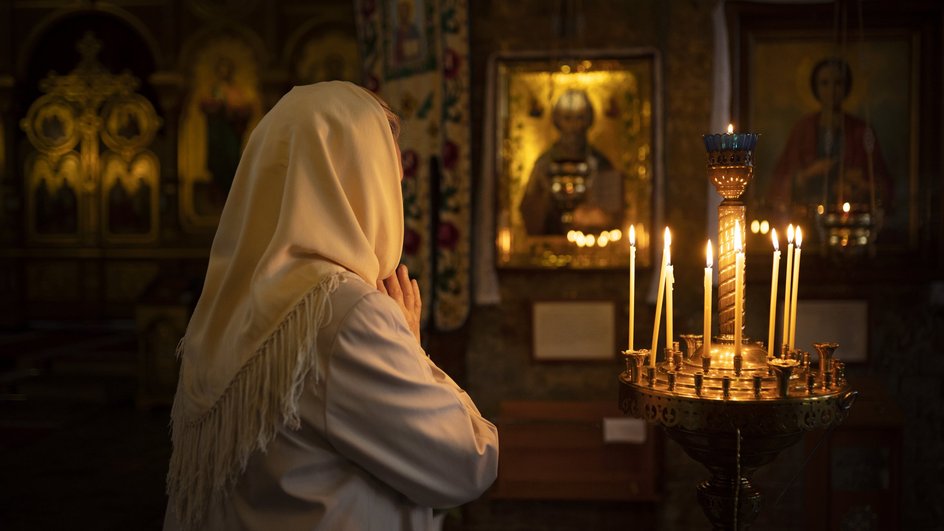 Женщина молится в храме в праздник Троицы