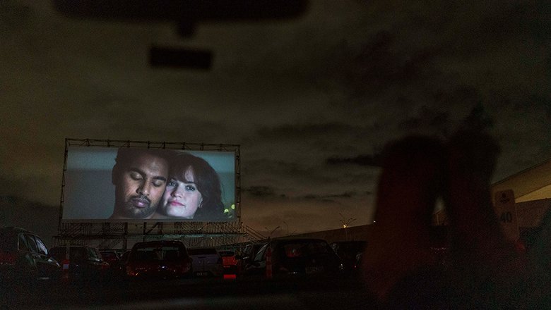 Люди наслаждаются фильмом на стоянке в международном аэропорту Карраско после того, как он был превращен в автокинотеатр. Монтевидео, Уругвай