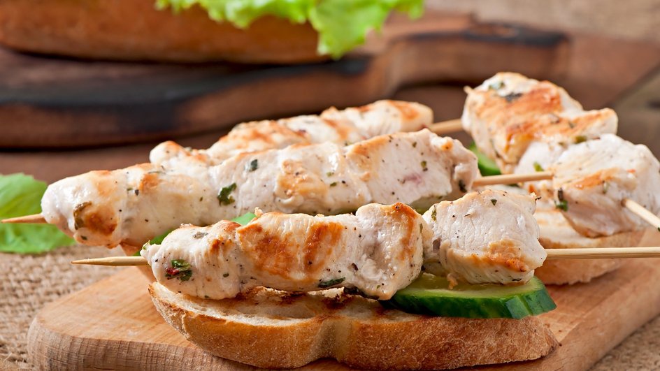 Мягкий куриный шашлык лежит на дольке огурца и хлебе Мягкий куриный шашлык лежит на дольке огурца и хлебе