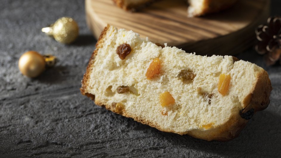 Кусочек пасхального кулича с цукатами и изюмом лежит на столе