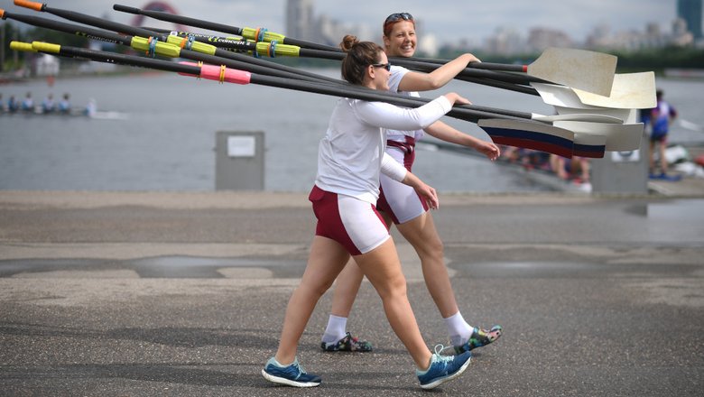 Спортсменки несут весла для гребли Спортсменки несут весла для гребли