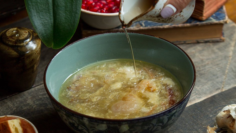 Девушка подливает масло в бульон для холодца из курицы и индейки Девушка подливает масло в бульон для холодца из курицы и индейки