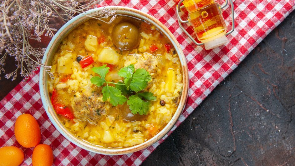 Тарелка супа с рисом и курицей стоит на столе рядом с ингредиентами
