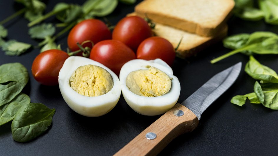 Ингредиенты для фаршированных яиц с беконом и кукурузой лежат на столе рядом с ножом