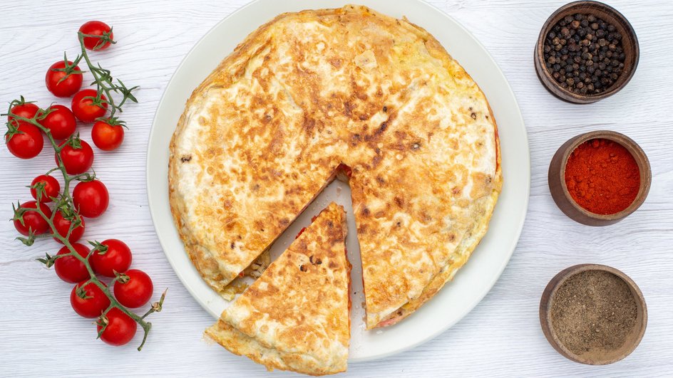 Блины с фаршем и сыром, приготовленные в духовке, лежат на тарелке рядом со специями Блины с фаршем и сыром, приготовленные в духовке, лежат на тарелке рядом со специями